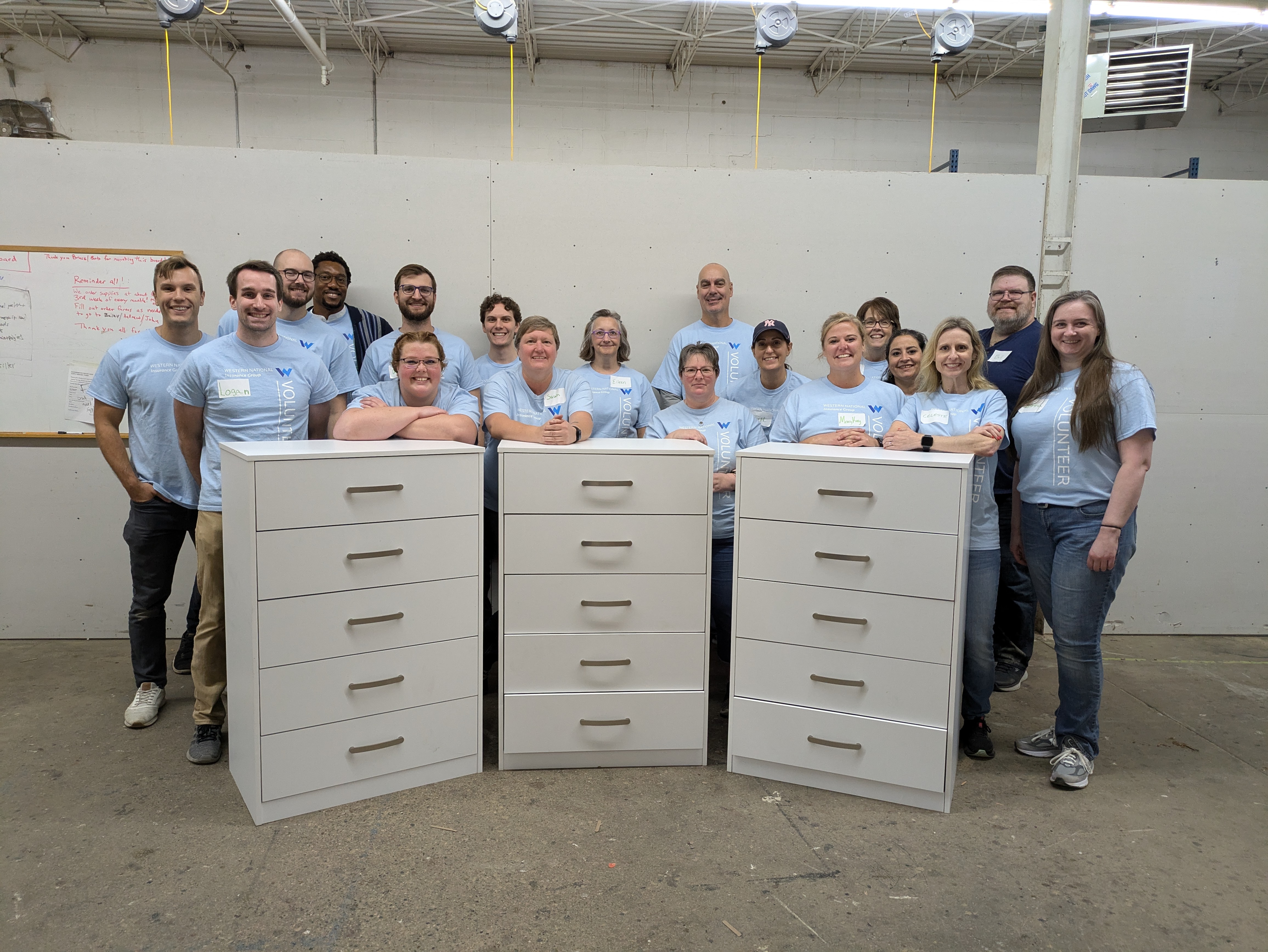 Western National employees standing behind three dressers they built at the Bridger Dresser Build volunteer event.